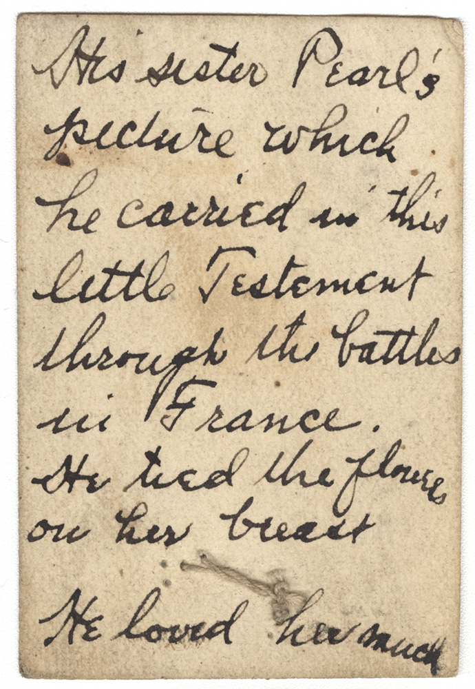 Back of a vintage photograph filled with handwritten text. Text: 'His sister Pearl's picture which he carried in this little Testament through the battles in France. He tied the flowers on her breast. He loved her much.'