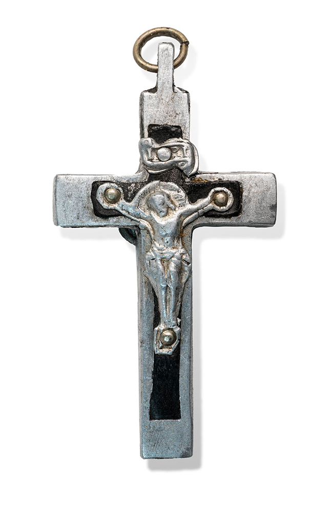 Front of a silver-colored cross-shaped pendant, with a silver-colored human figure depicted crucified on it