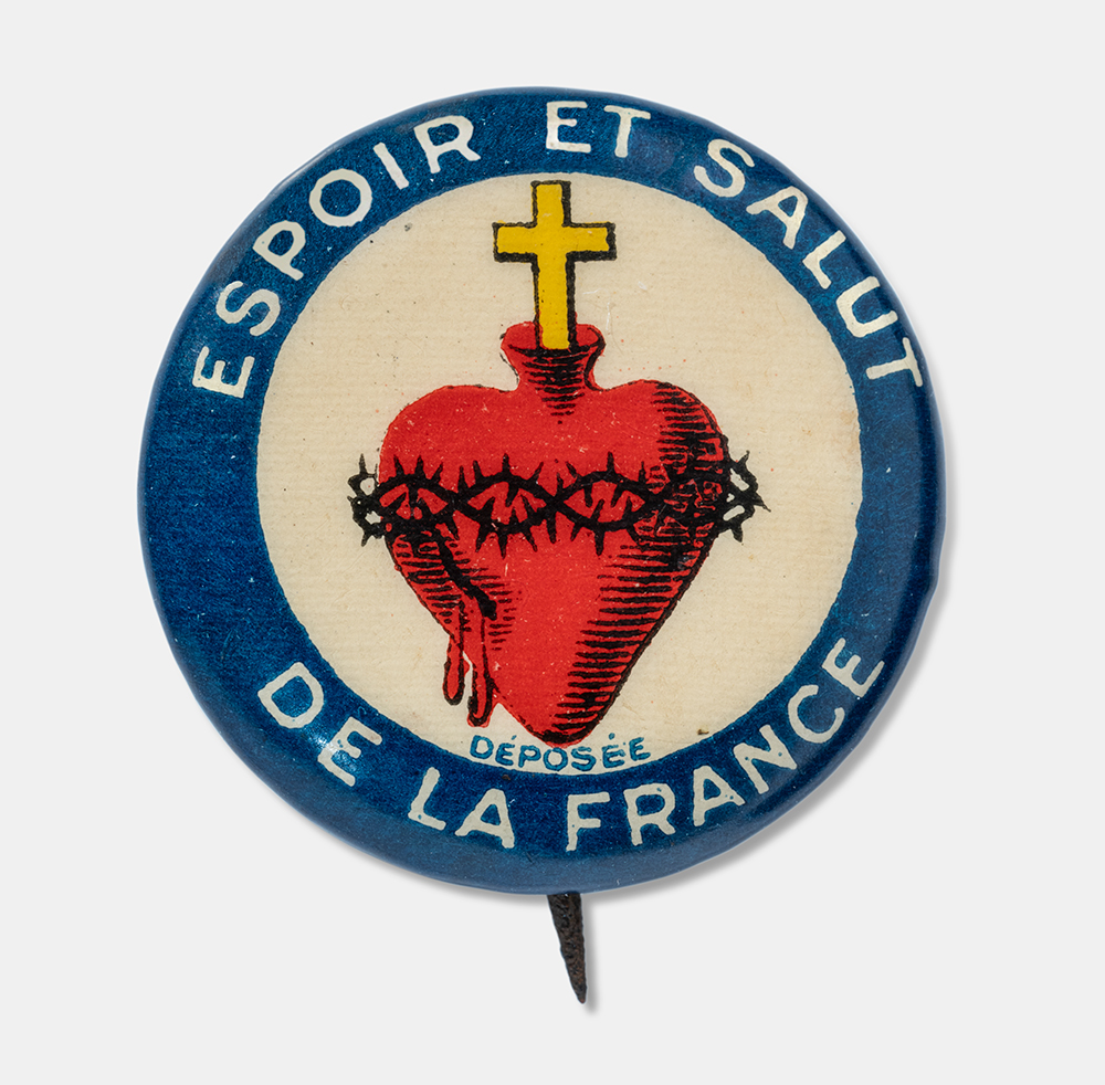 Circular pin with a blue border. The center depicts a red heart surrounded by a crown of thorns and topped with a cross. White text wrapping around the blue border: 'Espoir et salut / de la France'