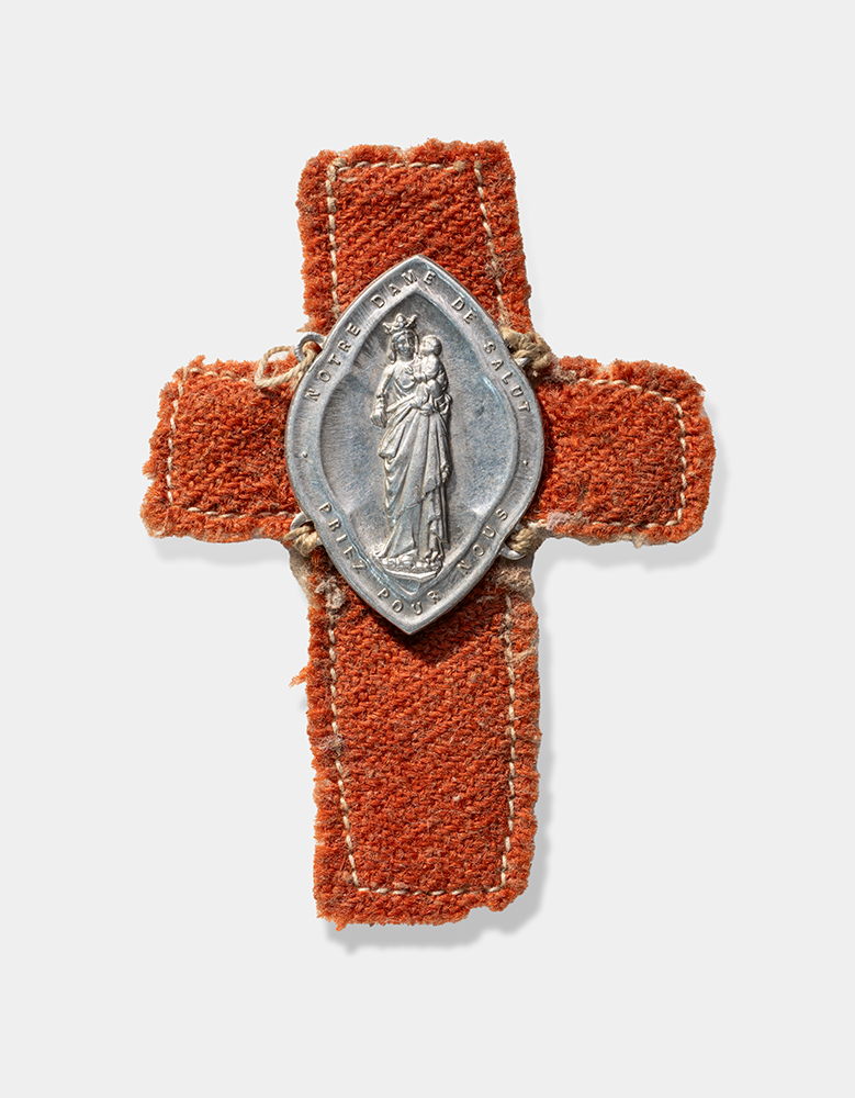 Silver-colored oval medal depicting a woman in robes holding a child. The medal is sewn onto a brown cloth cross.