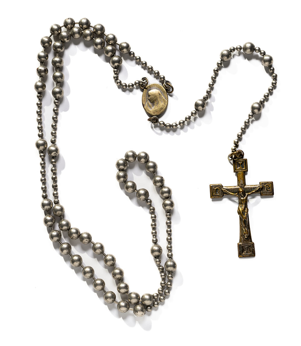 Dull bronze-colored crucifix pendant attached to a chain with different sizes of beads on it