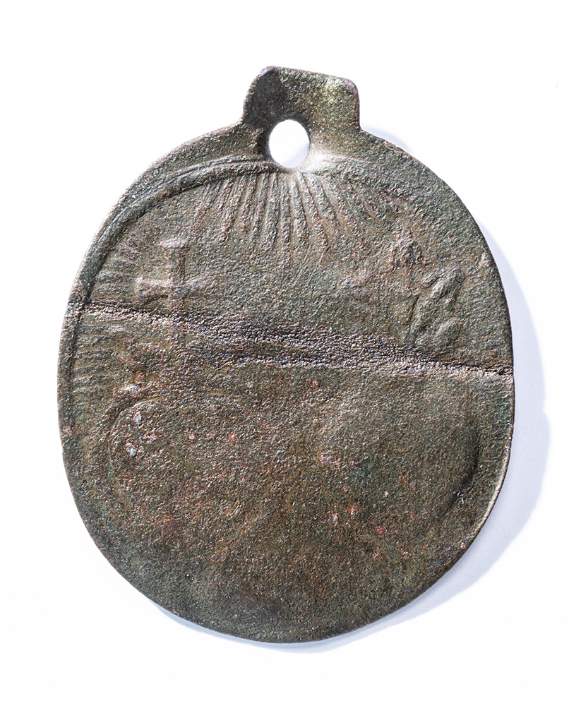 Dull grey-colored oval medal carved faintly with two smaller ovals, a cross, and other faint symbols