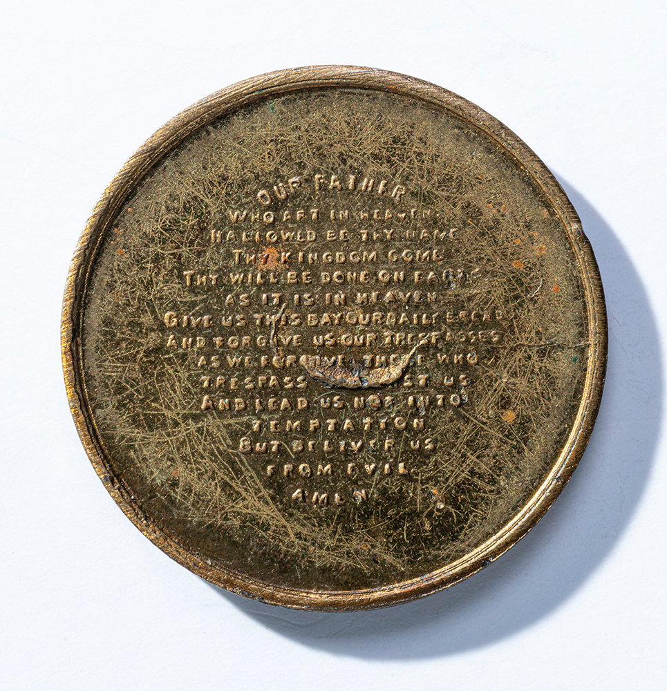 Back of a brass-colored coin engraved with the Lord's Prayer in small text