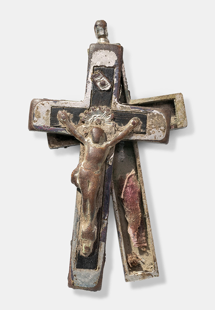 Front and back of a pewter-colored crucifix slid away from each other to reveal a hollow space containing a scrap of aged cloth
