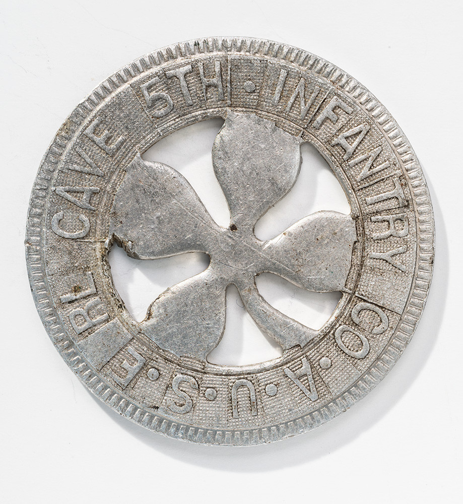Silver-colored coin with a four-leaf clover in the center. Text is engraved around the border.