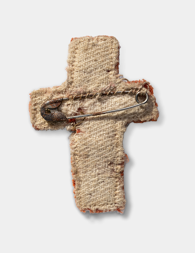 Back of a cloth cross. A safety pin is attached.